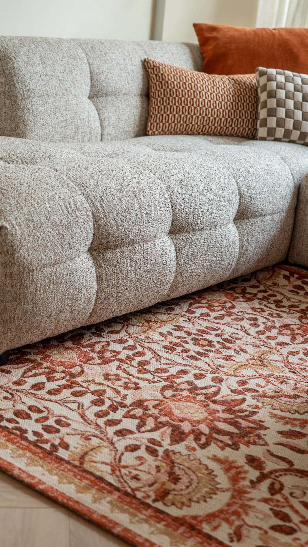 Retro zithoek met zandkleurige hoekbank en kleurrijk vloerkleed in terra