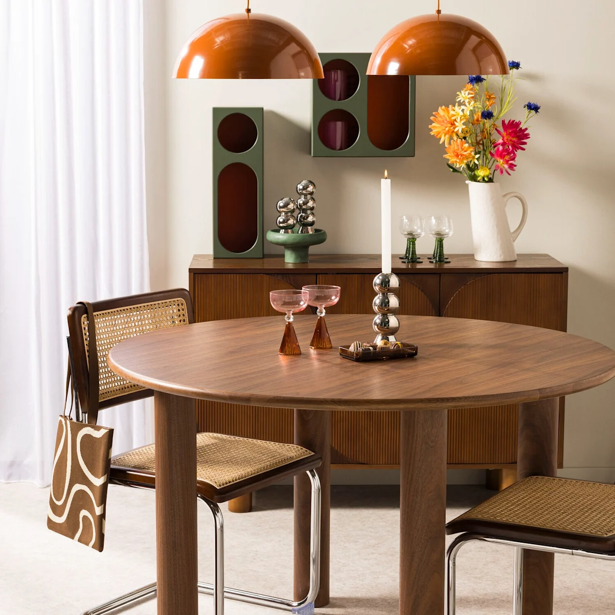 Retro eethoek met donkerhouten ronde eettafel, rotan eetstoelen, terra hanglampen en retro accessoires.