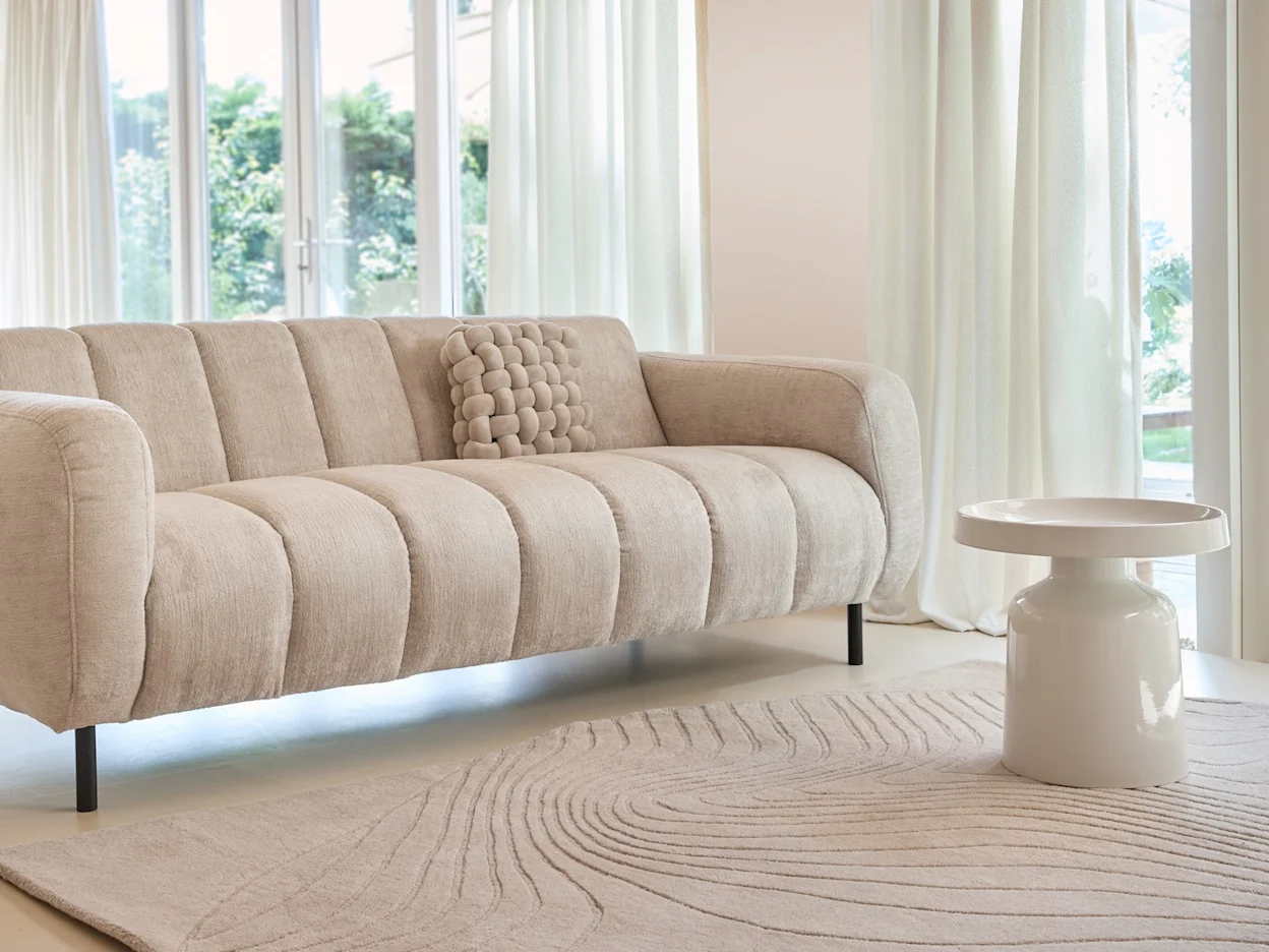 Moderne zithoek met een grijze strakke bank en een hoogglans bijzettafel