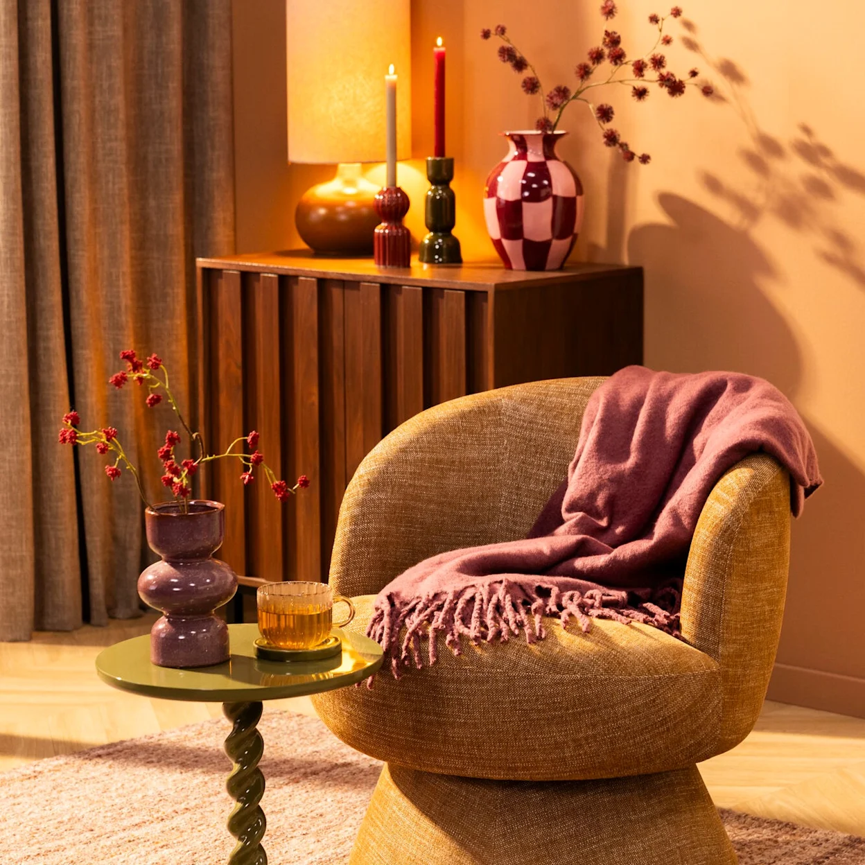 Fauteuil met woonaccessoires: kandelaars, vazen en een plaid