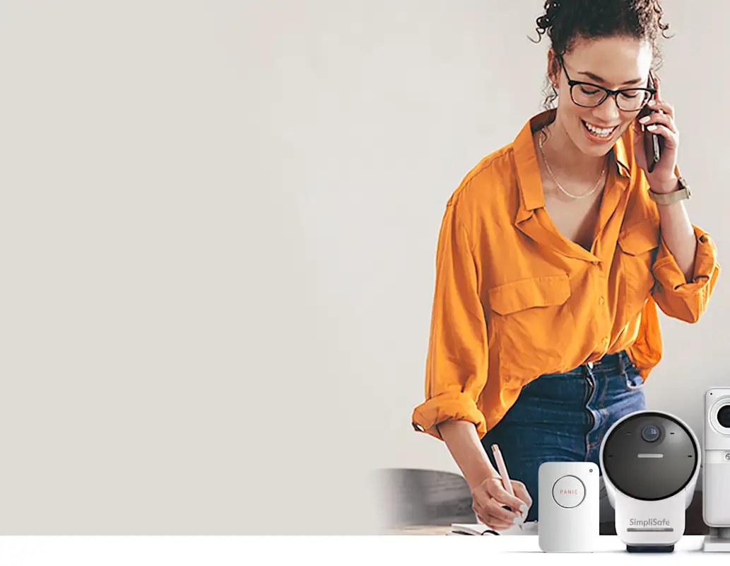 Image of woman with home security products, including a panic button, an outdoor camera, and an indoor camera