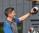 Image of a professional installer mounting an outdoor camera to the side of a home