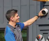 Image of a professional installer mounting an outdoor camera to the side of a home