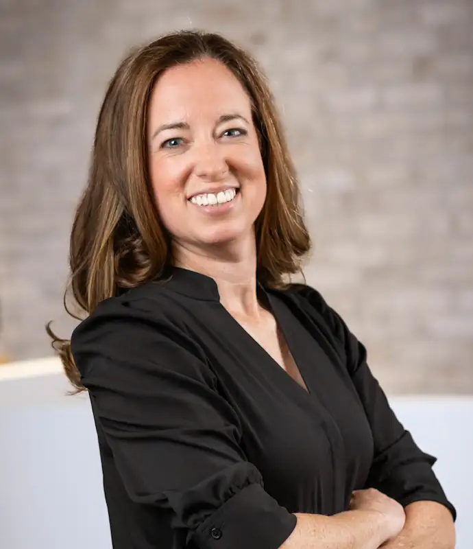 Crystal Caligiuri smiling and standing with arms crossed in an indoor setting.