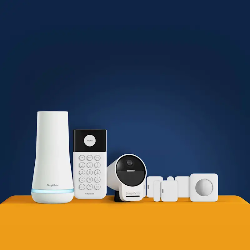 SimpliSafe home security kit displayed on an orange surface with labeled components: Base Station, Keypad, Outdoor Camera, Entry Sensors, Motion Sensor, and Yard Sign. Text reads: 'Monitored 24/7 SimpliSafe Home Security.' Gold badge reads: 'SimpliSafe 60-Day Money-Back Guarantee.'