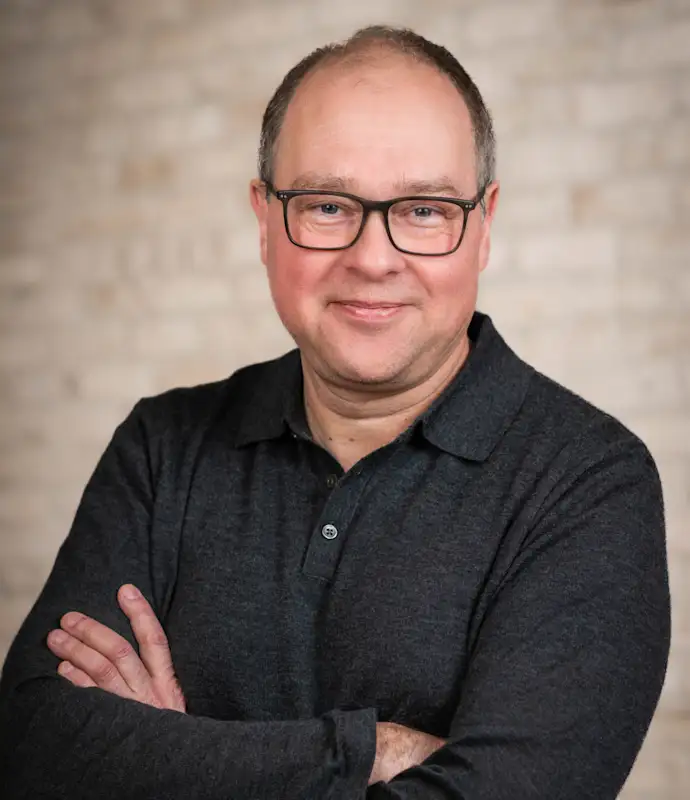 Christian Cerda standing with arms crossed in an indoor setting.