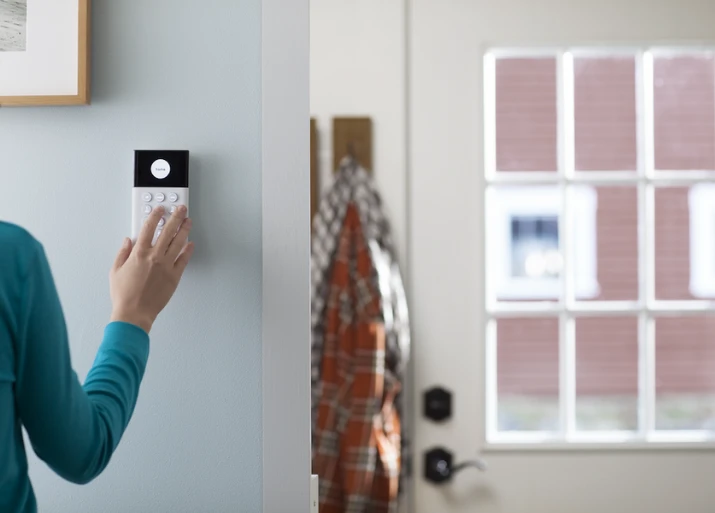 Image of a keypad mounted to a wall and someone arming it