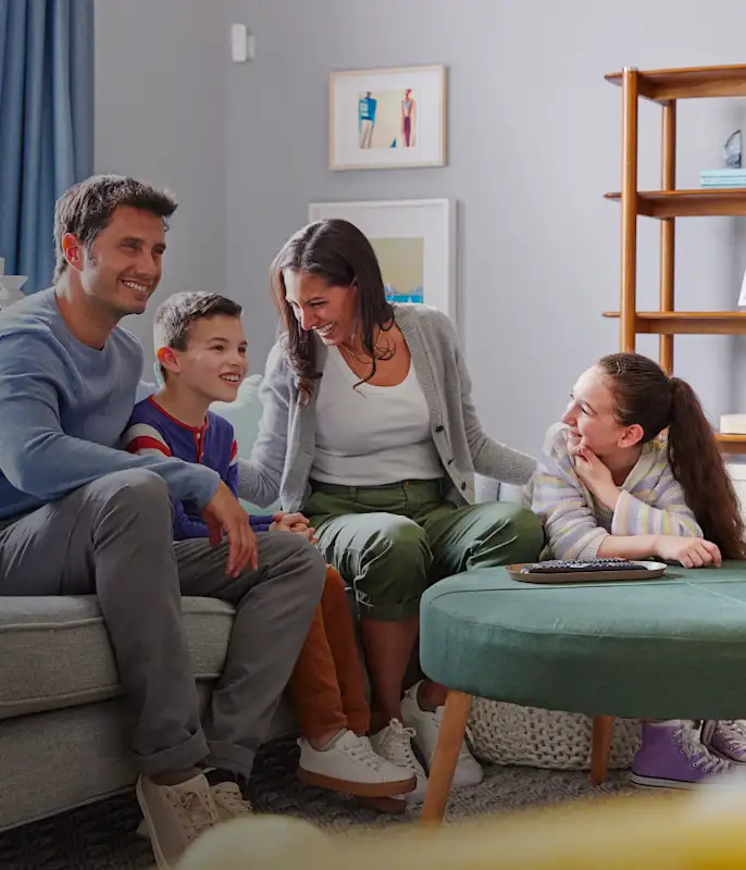 Image of a family in their living room with a home security camera mounted to the wall