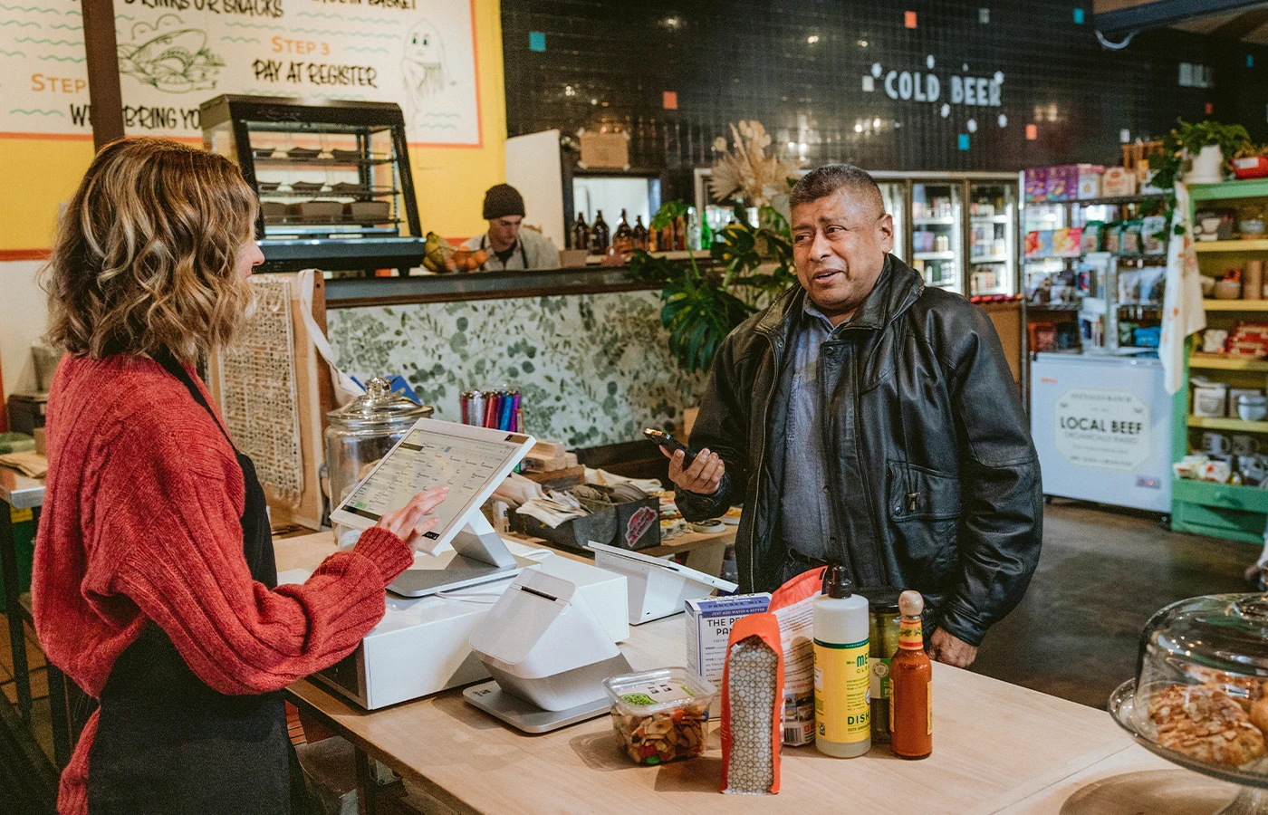 Customer speaking with convenience store employee at counter. 