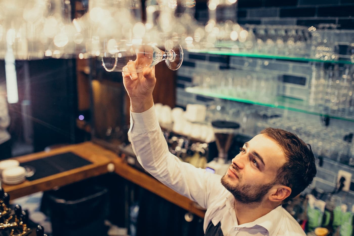 Bartender stocking glasses behind a bar