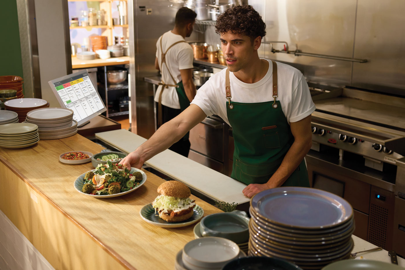 A kitchen staff member passes a plate of food across a counter. 