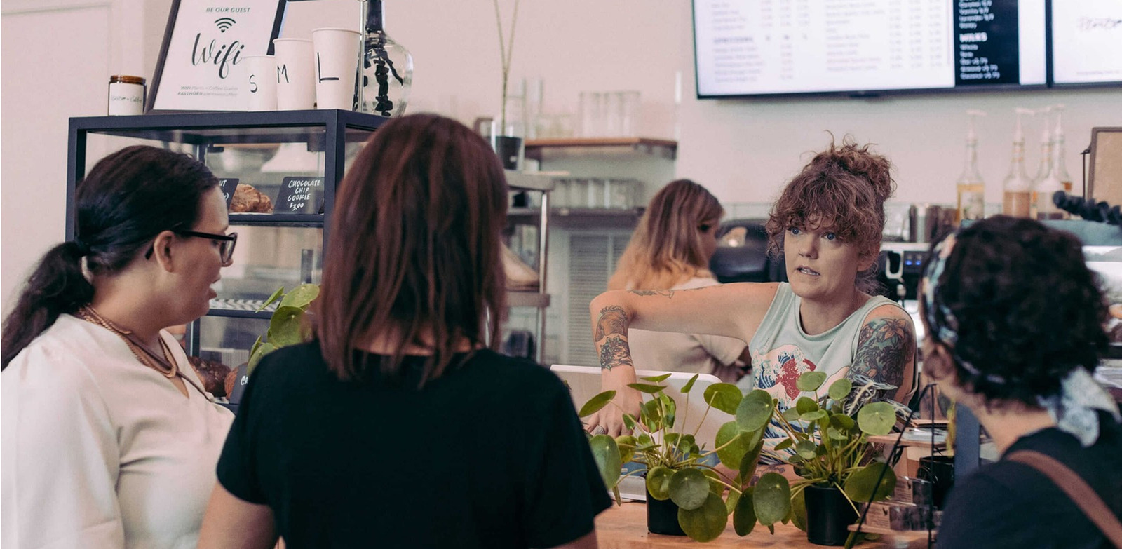 Customers are ordering at the coffee shop, and a shop owner is taking order on clover device.