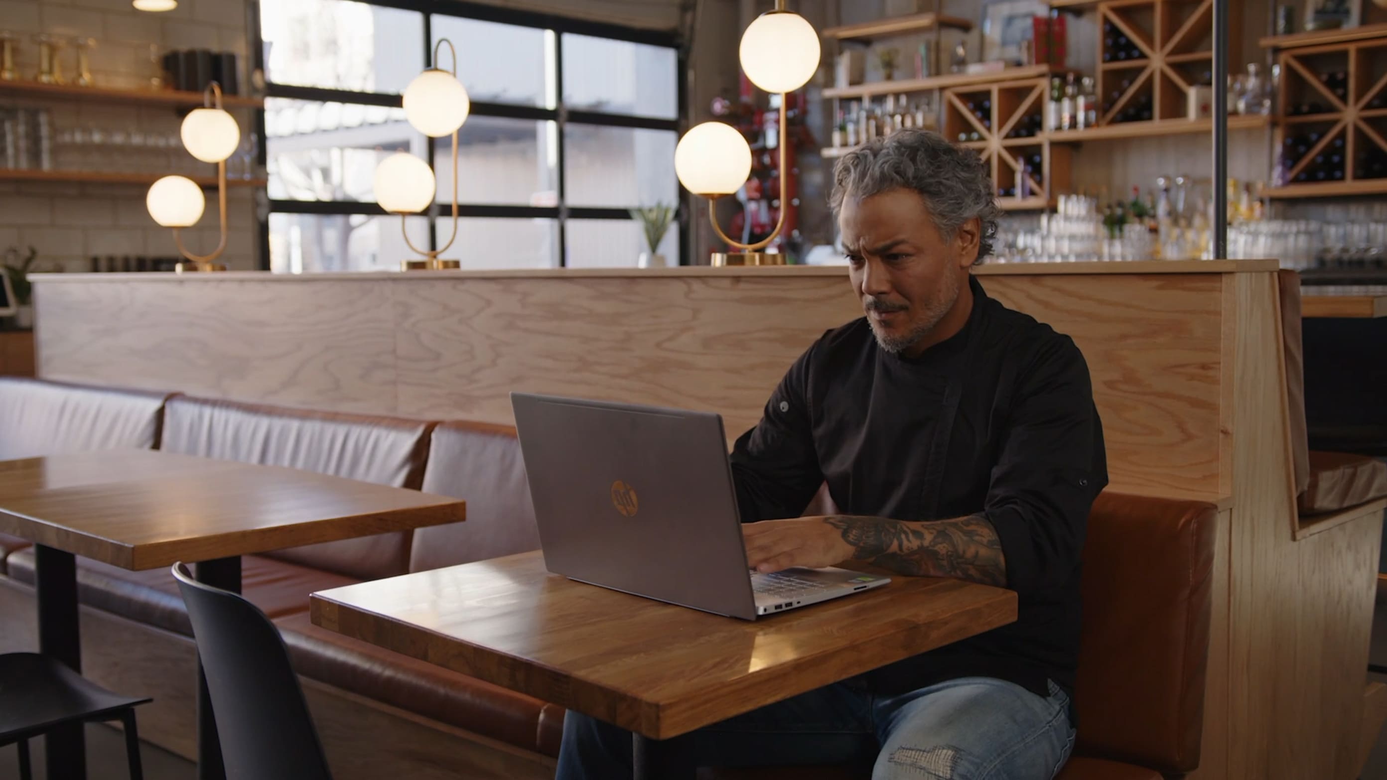 A man sitting at the bar working on laptop.