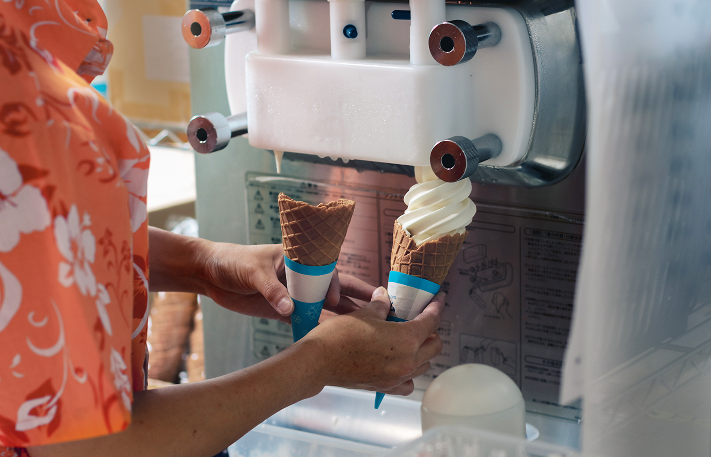 Store attendant serves up two cones of frozen yogurt from frozen yogurt machine