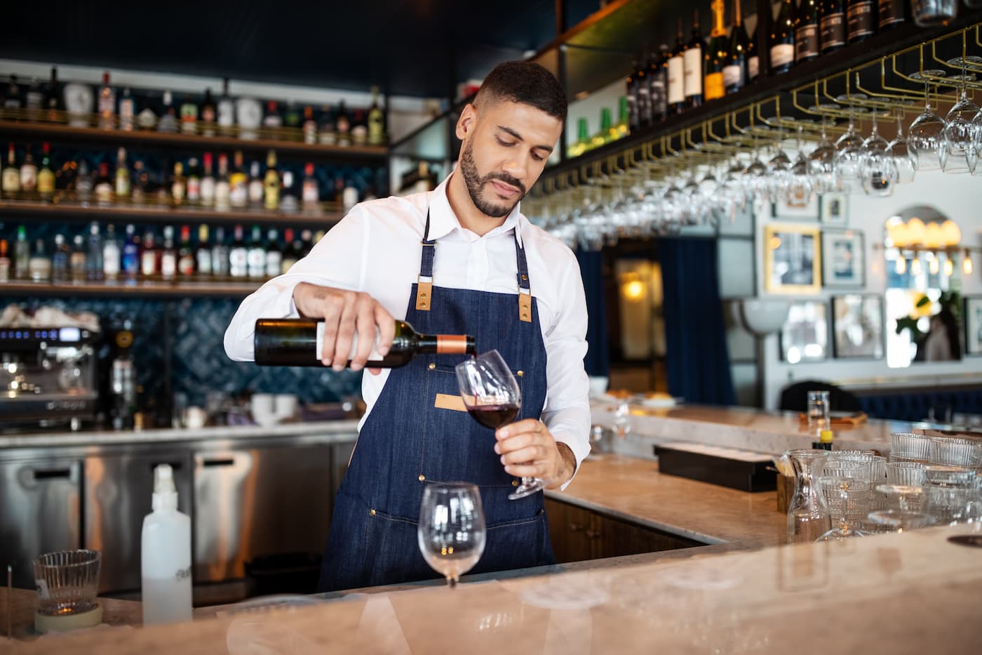 Bartender pouring a glass of red wine