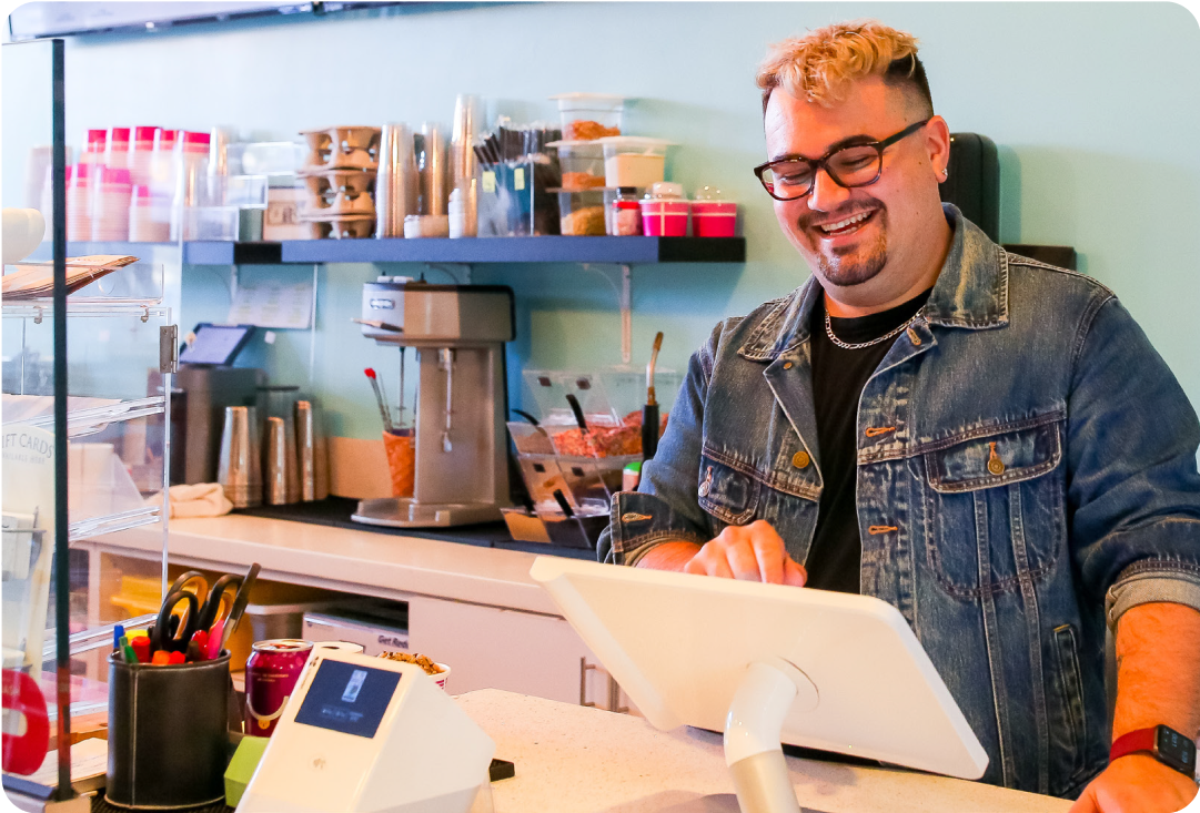 Merchant standing behind a counter smiling at their dessert shop using a station solo device