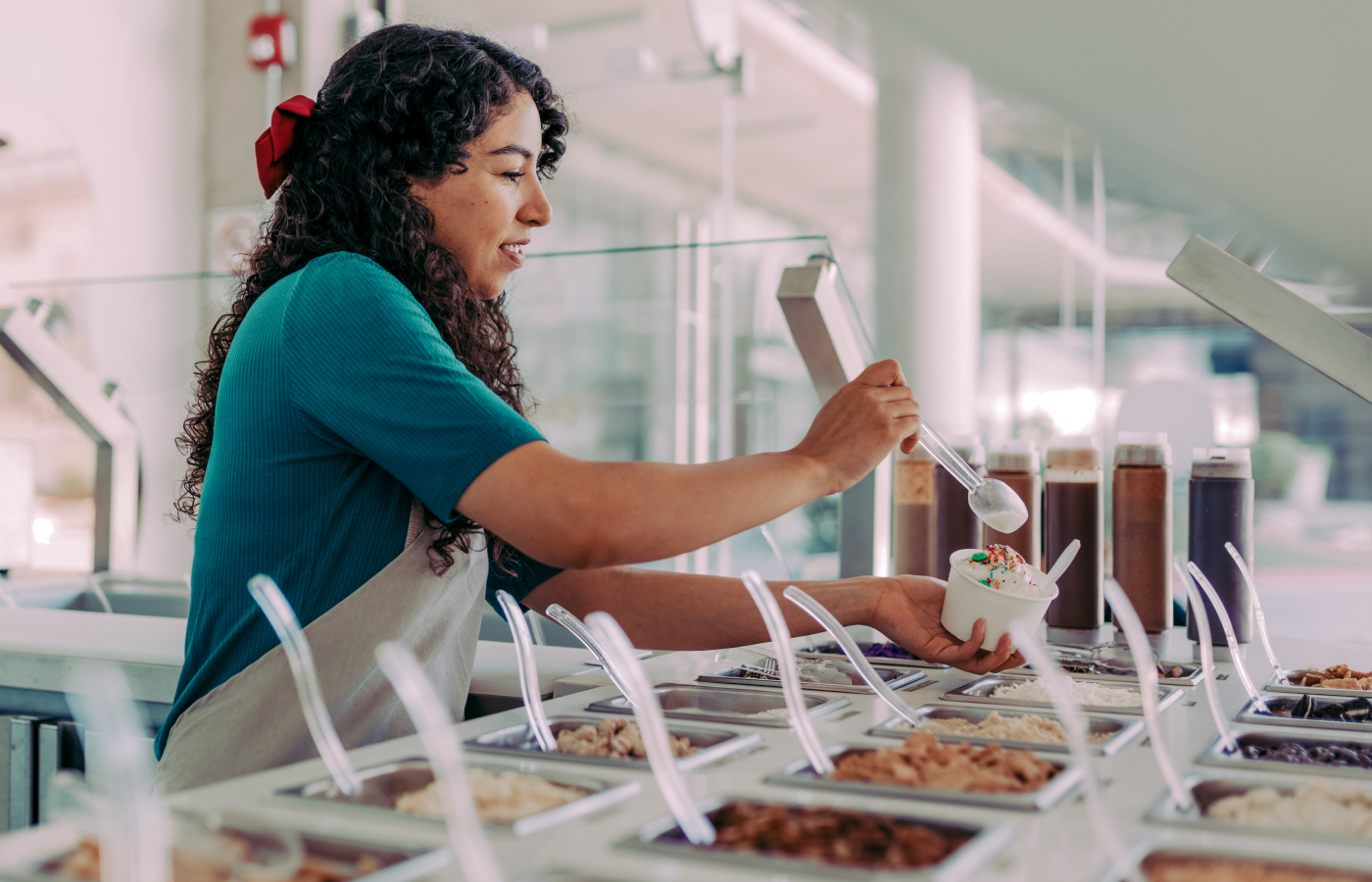 Woman puts toppings on a serving frozen yogurt