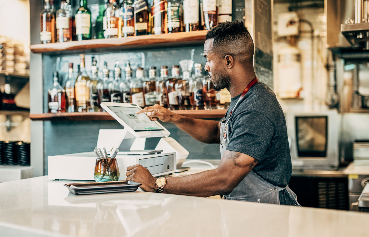 Chef standing behind a counter in front of a cash drawer adding an order into a machine