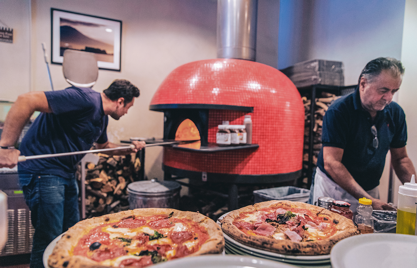 Workers serve up two pizzas from pizza oven 