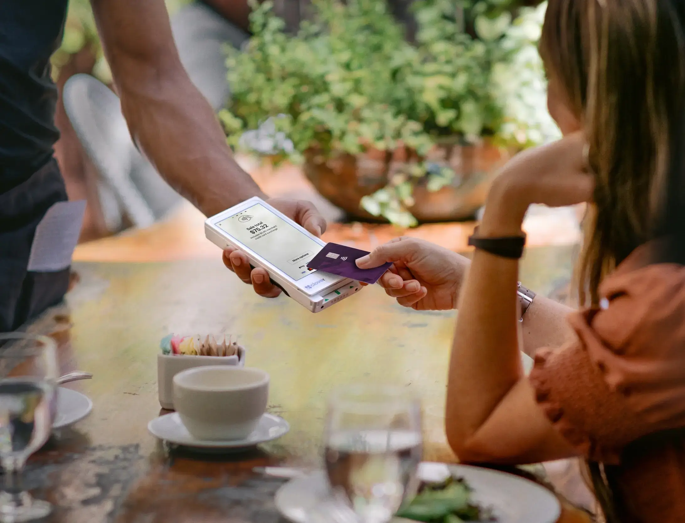 Woman at a restaurant tapping credit card to pay for meal on a Flex Pocket.