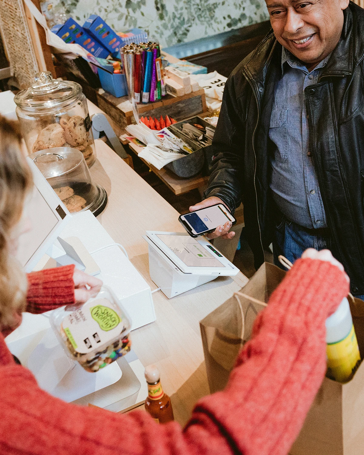 Image of a man in a retail market using a contactless payment method to purchase items