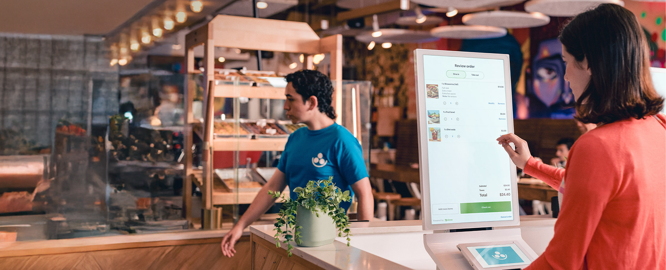 Woman in restaurant browsing menu items on a touch-screen kiosk.