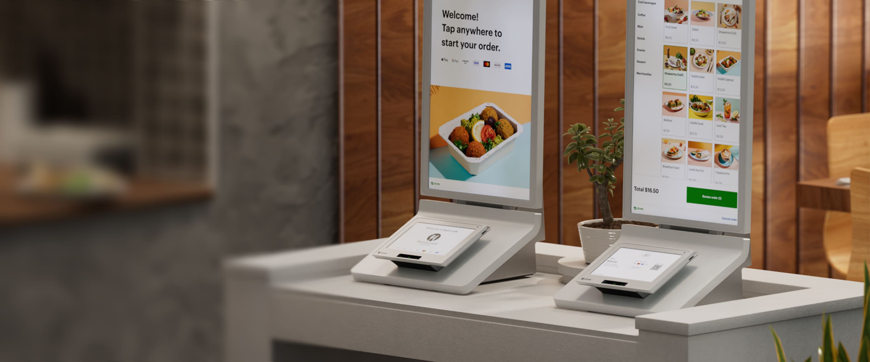 Two Clover Kiosks sit on partially blurred counter; left has welcome message, right has stacked food menu, images, prices.
