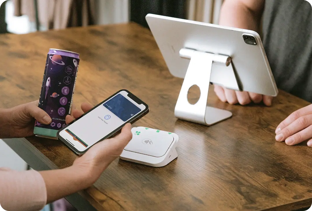 Customer making a contactless payment with his phone on a Clover Go while holding an energy drink.
