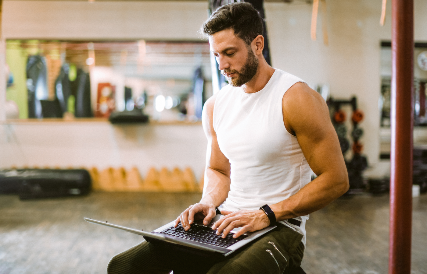 Man working on laptop in gym. 