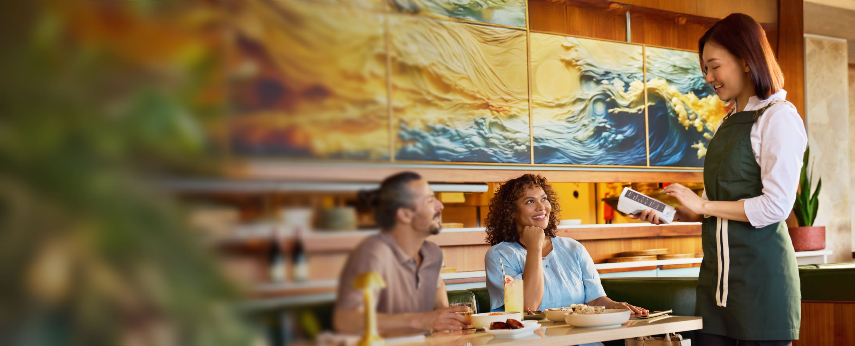 Image showing the waitress is taking food order from customers on the device, at the restaurant. Few of the food items are kept on the table.