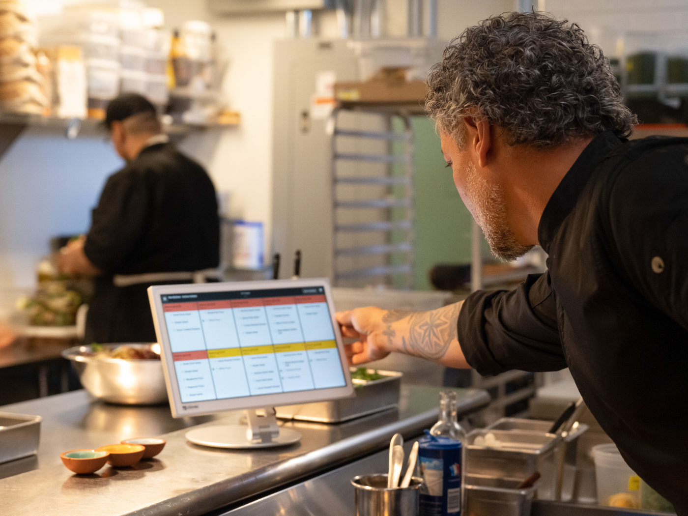 Chef holding bezel of kitchen display system while looking at orders.