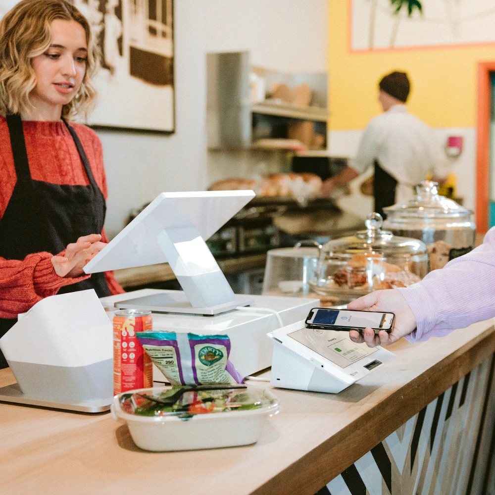 Barista rings up customer for lunch, customer uses tap to pay to complete their purchase.