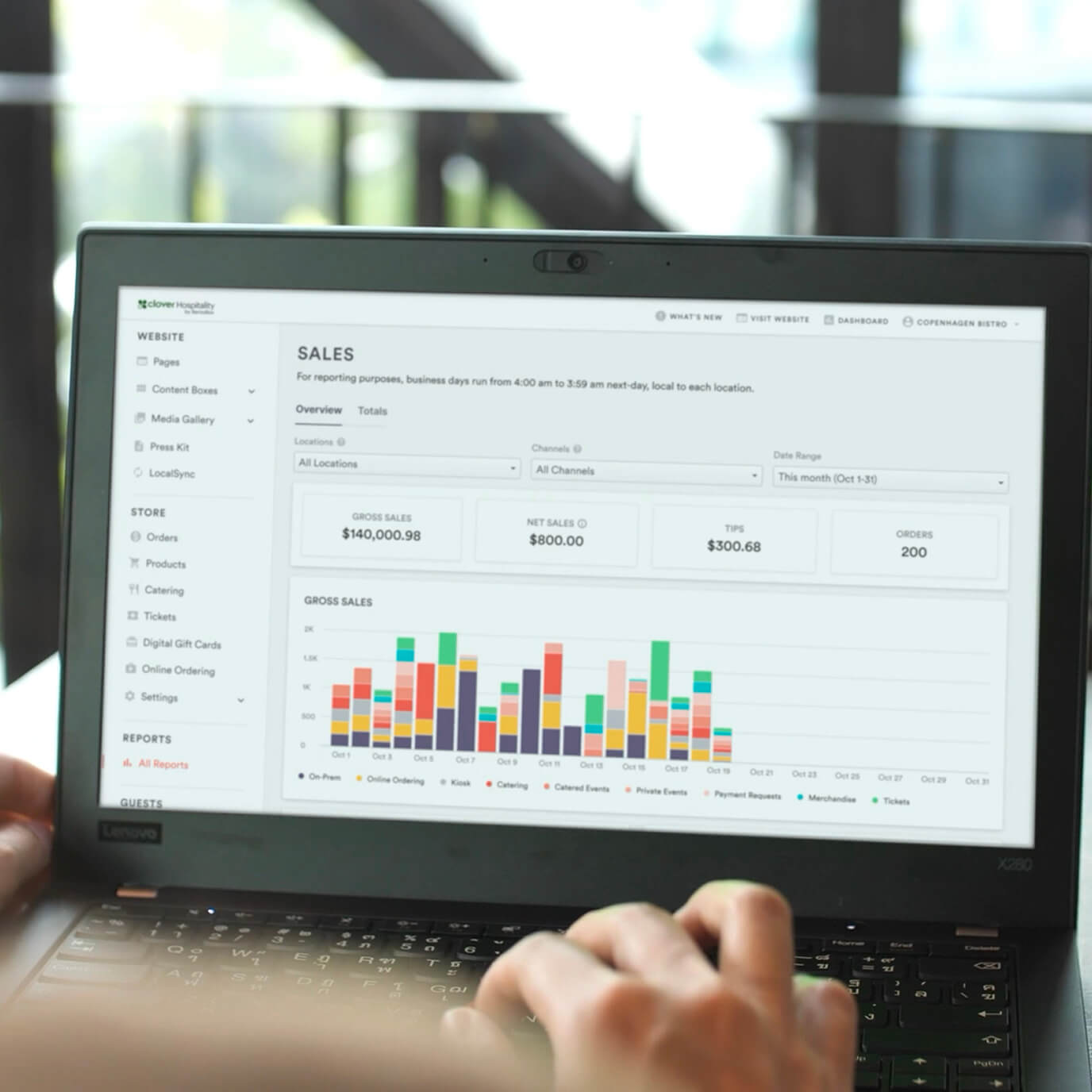 Person using Clover dashboard to review metrics include gross sales, tips, orders, and bar chart by channel for October.