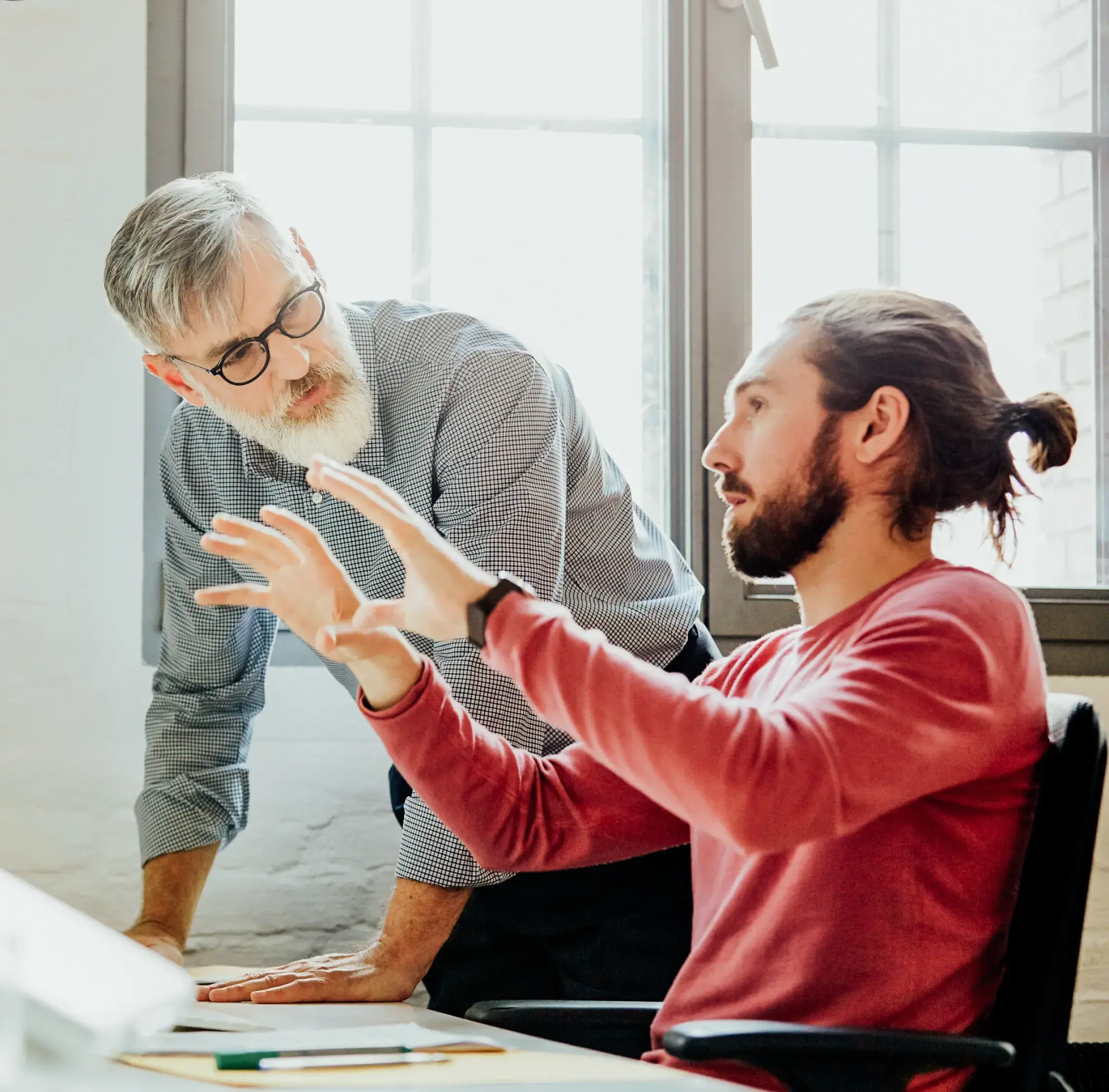 Man gestures with hands while discussing with another man beside him.