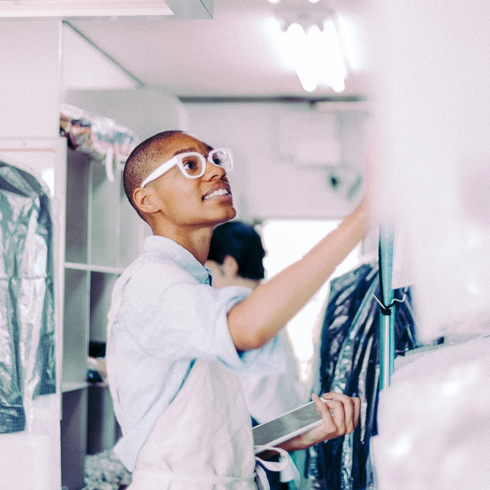 Dry cleaner employee holding tablet and looking for item.