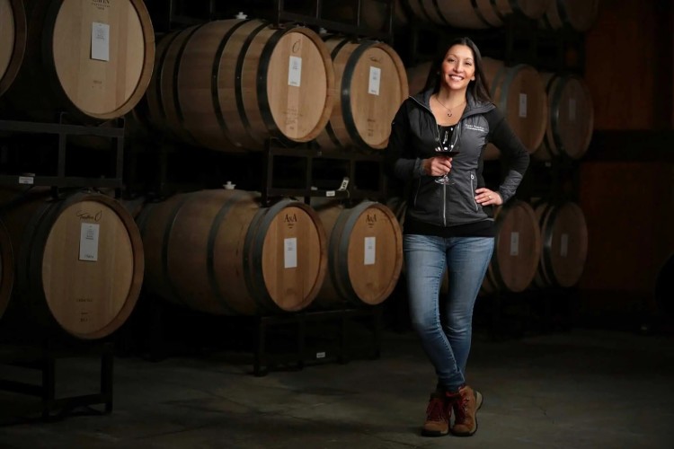 Head winemaker Theresa Heredia of Gary Farrell Winery standing with pinot noir barrels. 