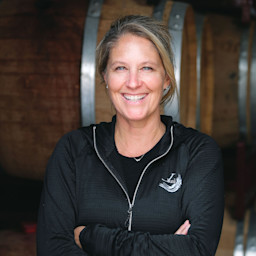 Janell Dusi standing in front of barrels.