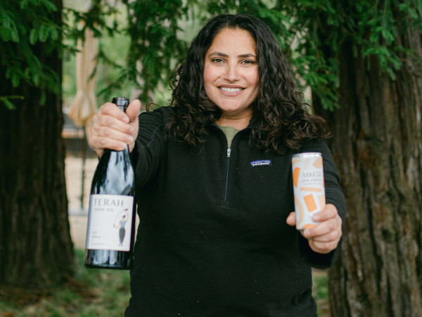 Winemaker Terah Bajjalieh of Terah Wine Co holding a bottle and a can of Orange Vermintino.