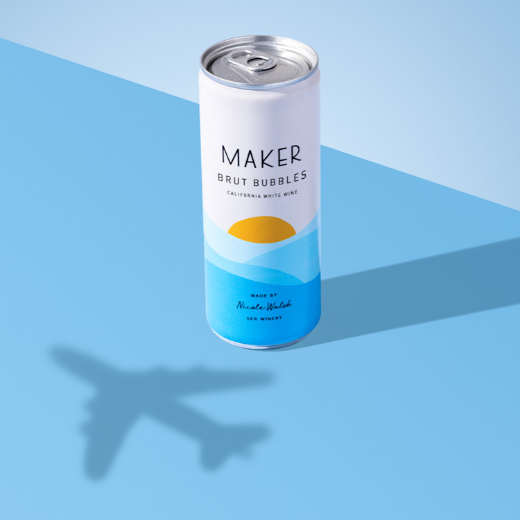 can of maker wine brut bubbles with an airplane shadow on a blur backdrop