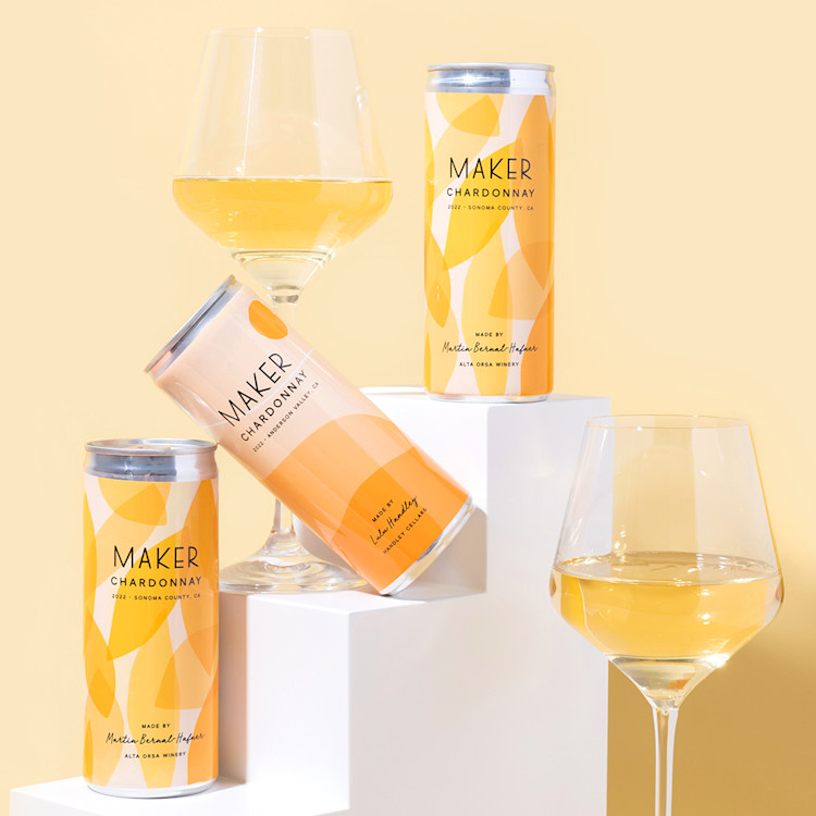 Three cans of Maker Wine sitting alongside two glasses of wine.