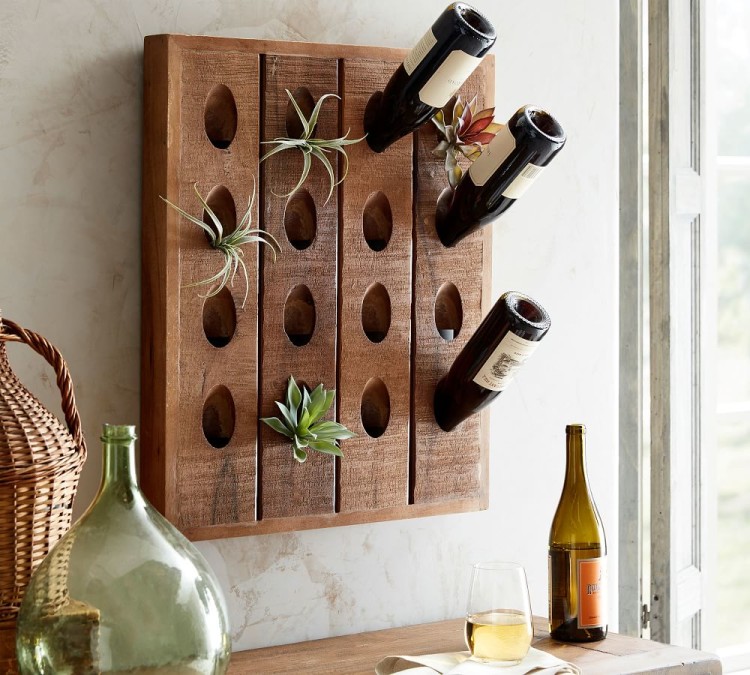 Wine bottle rack fixed to a wall with three wine bottles and succulent plants