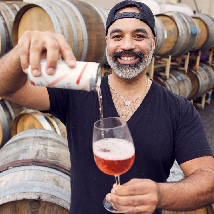 Chris Christensen of Bodkin Wines pouring a can of Sparkling Rosé into a glass.