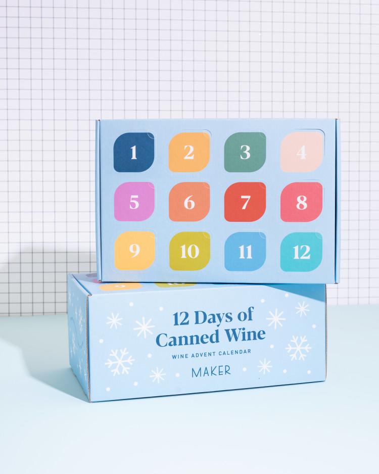 Two advent calendar boxes. The first shows the twelve days that can be opened to reveal cans of wine, while the other shows the "12 Days of Canned Wine" title. Three cans of wine sit next to the boxes.