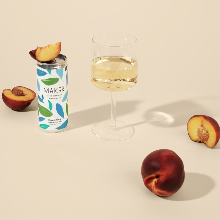 A can and glass of 2019 Viognier alongside a few peaches.