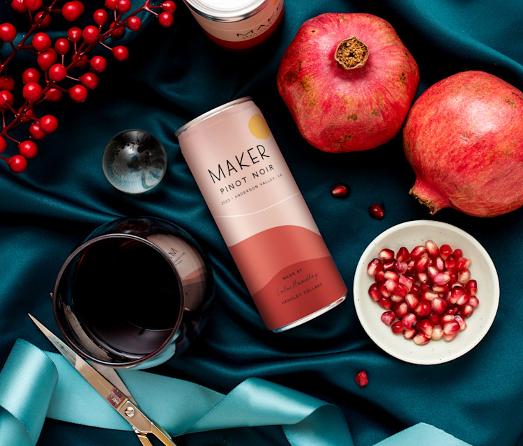 Maker Wine cans of Pinot Noir laying next to decorative items.