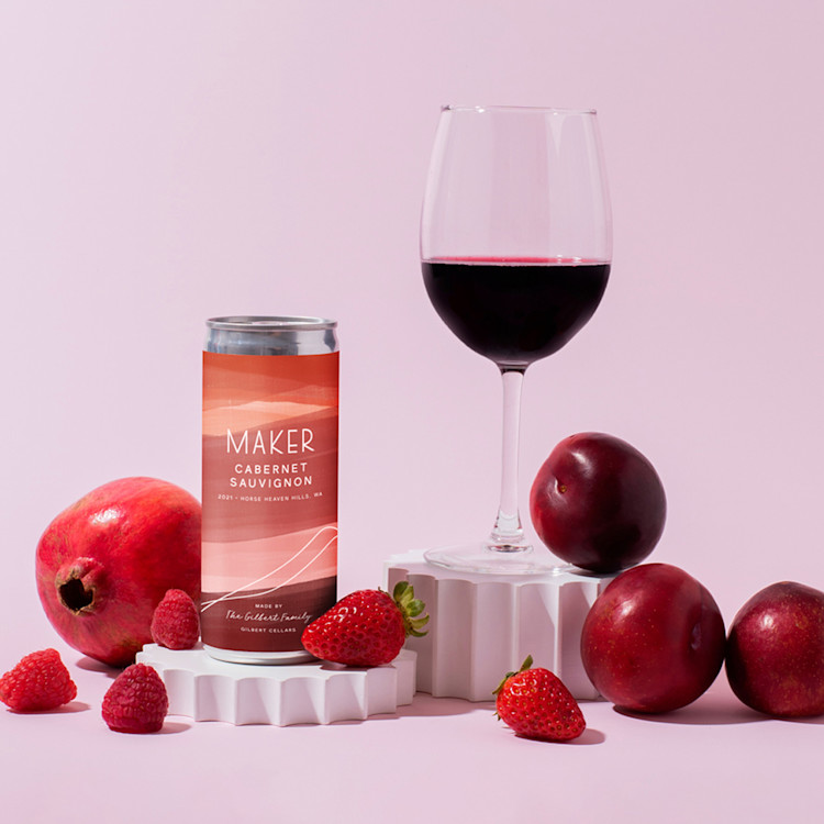 A cans of Maker Wine's Cabernet Sauvignon sitting alongside a glass of wine and fruit.