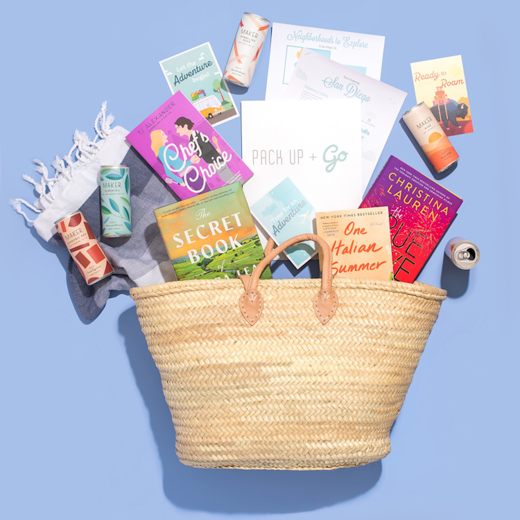A basket displaying the contents of the giveaway: cans of wine, books, and a piece of paper with the Pick Up & Go logo.