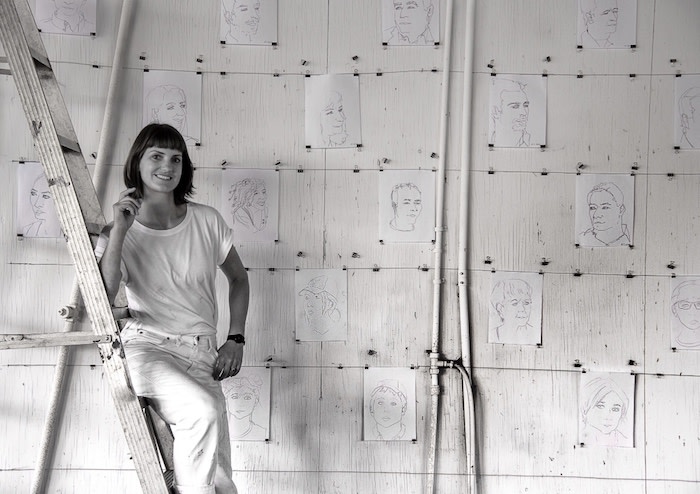 Alice Sutro standing on a ladder next to her art