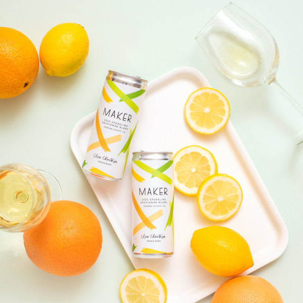 Maker sparkling sauvignon blanc on a tray with citrus fruits and glassware.