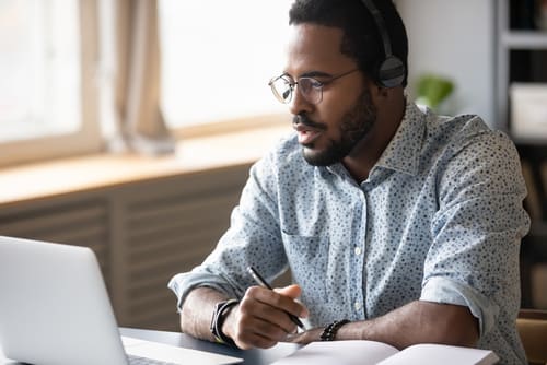 a man working on a laptop making notes